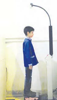 دانش‌آموز در حال اندازه‌گیری قد و وزن خود